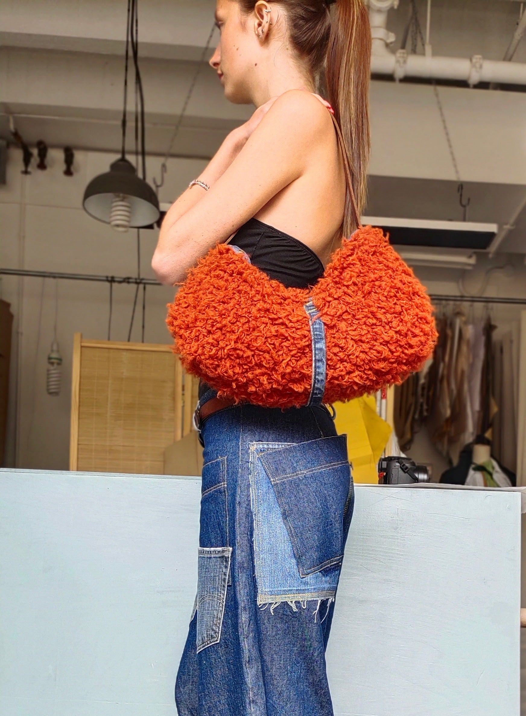 Person holding an orange textured bag in a clothing store.