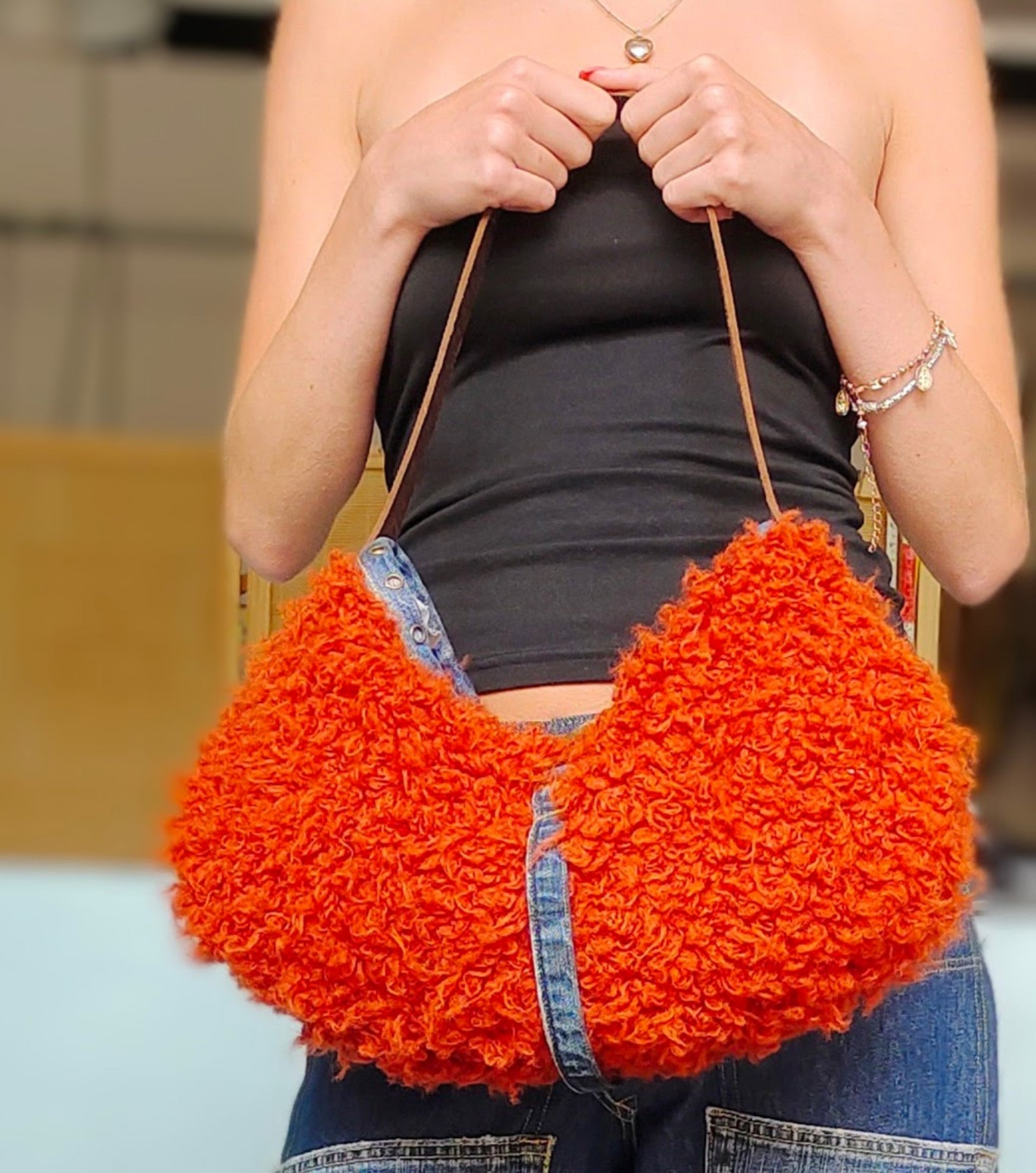 Person holding an orange textured handbag 